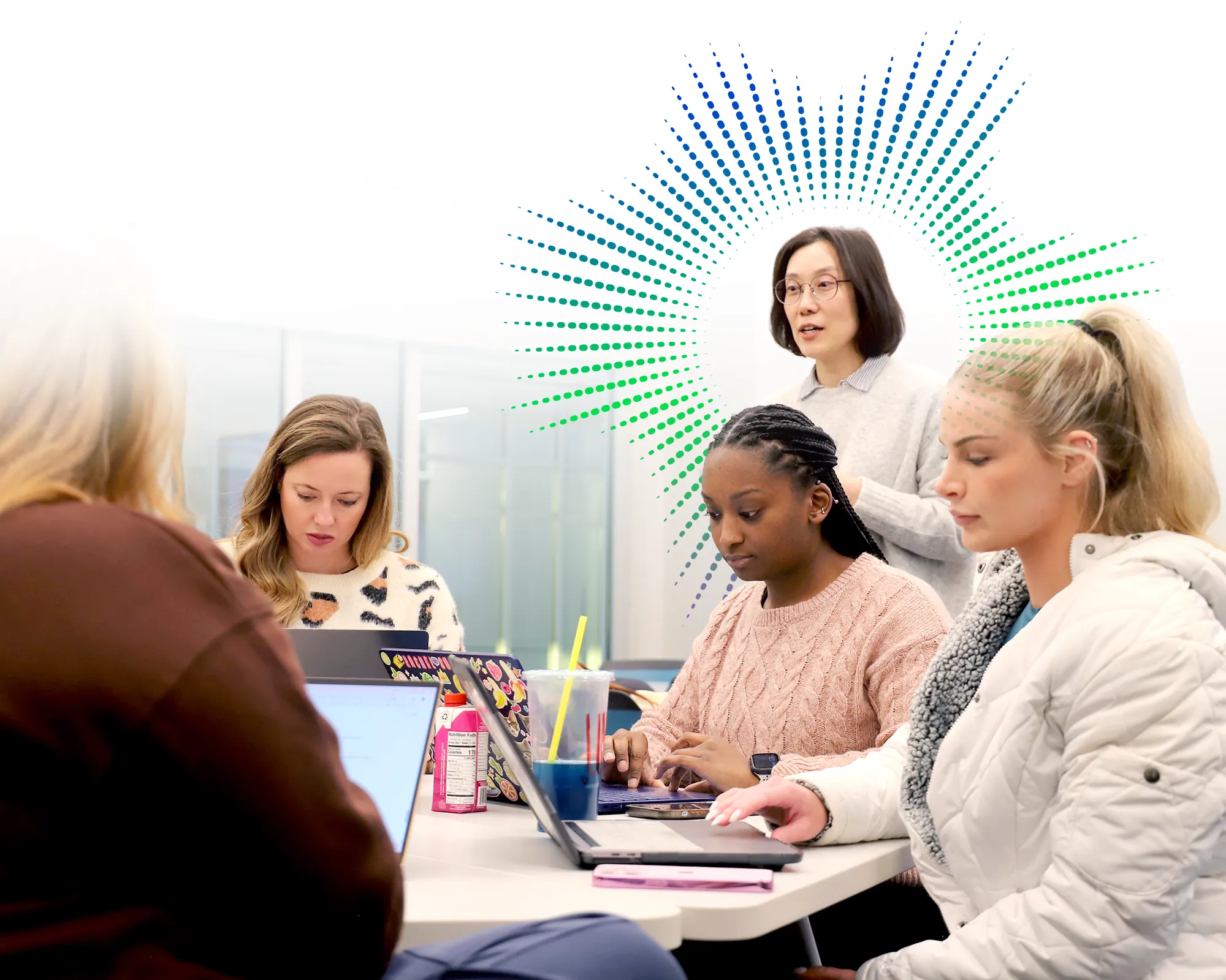 Dr. Park stands and speaks with students working on laptops around a classroom table.