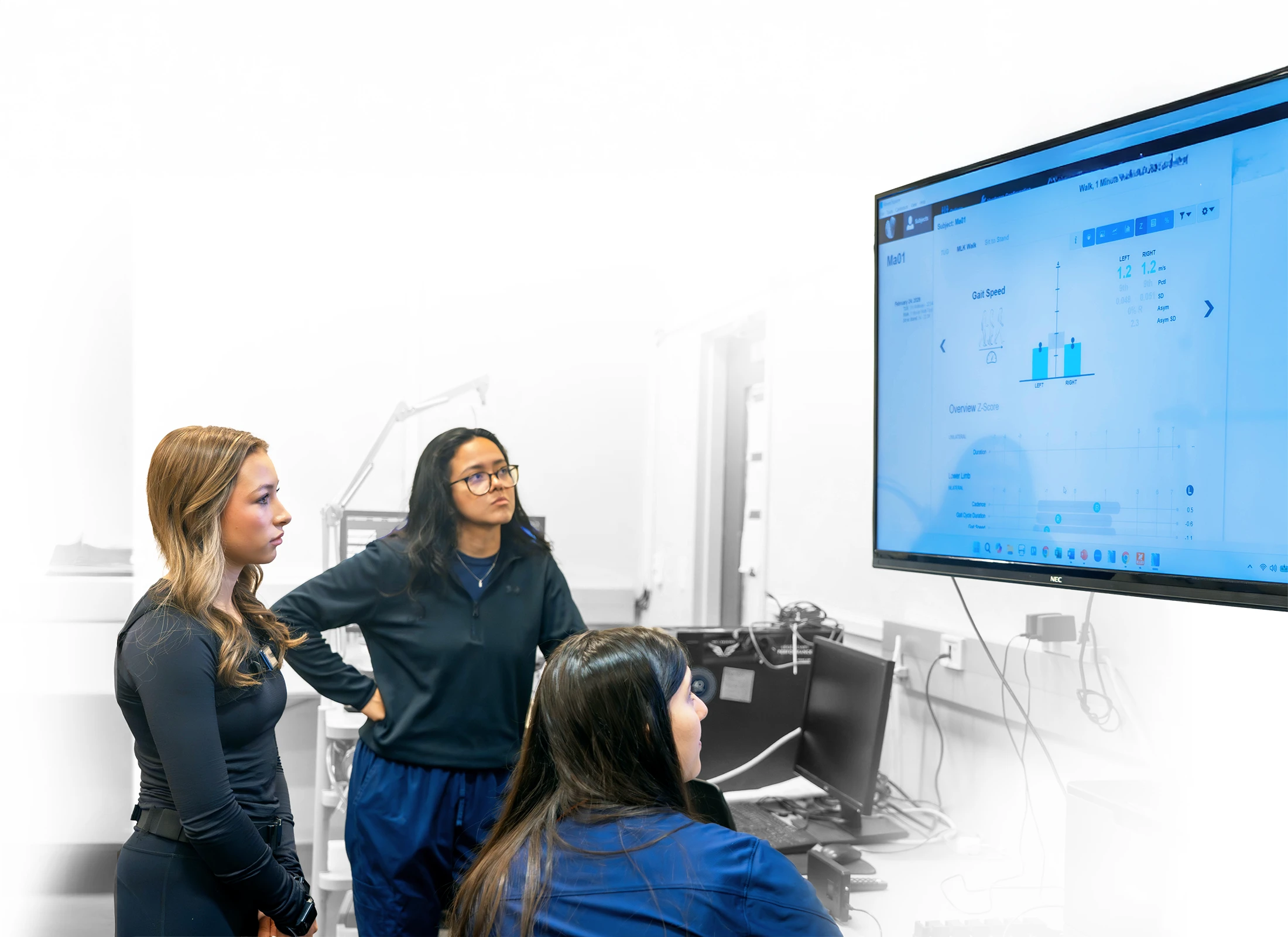 Eva Litkenhous and Auburn researchers review gait data on a wall-mounted monitor in the Locomotor Lab.