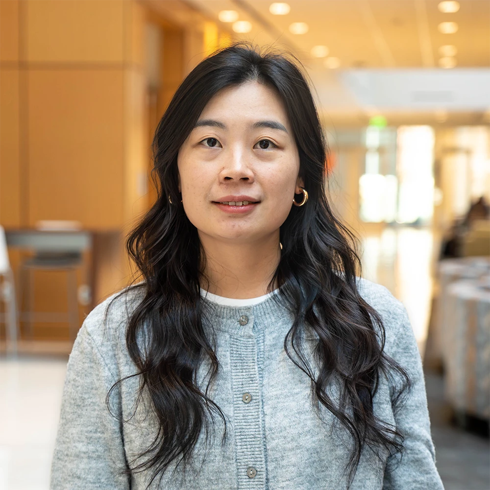 Dr. Lyu in a head-and-shoulders portrait wearing a gray cardigan in a campus building.